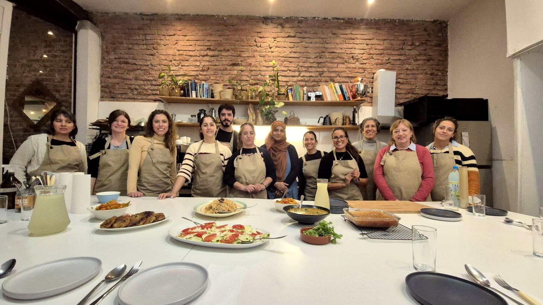Un grupo detrás de la mesa larga del estudio, con los platos que cocinó
