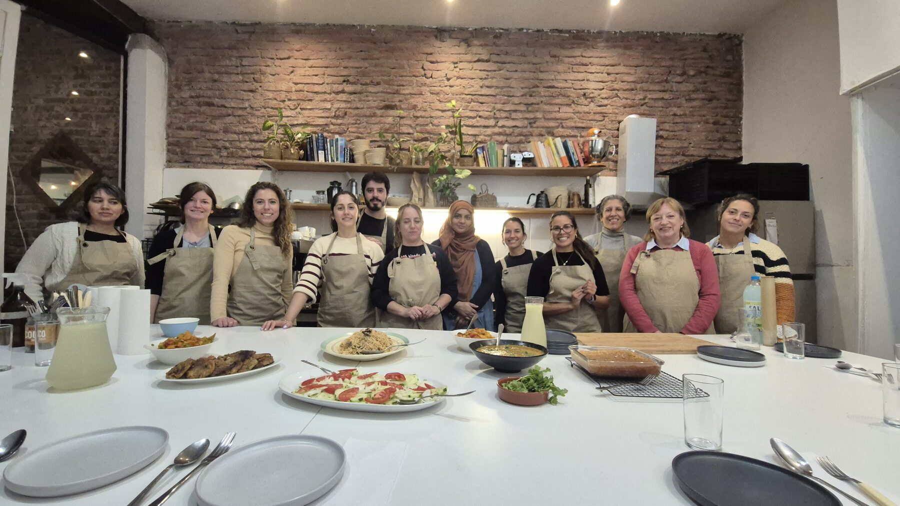 El grupo entero al final de una clase, detrás de la mesa con todo lo que cocinaron