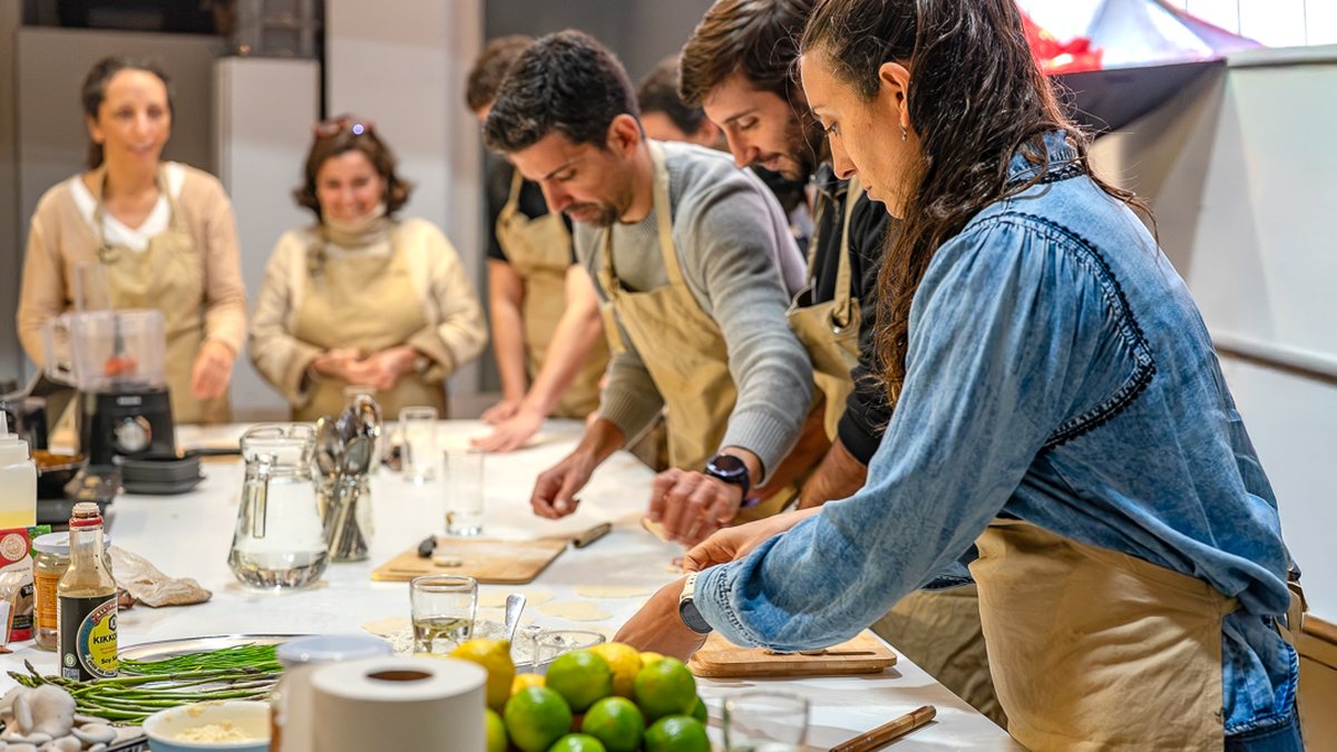 El grupo cocinando alrededor de la mesa grande en la Cena y Taller de Tapeo
