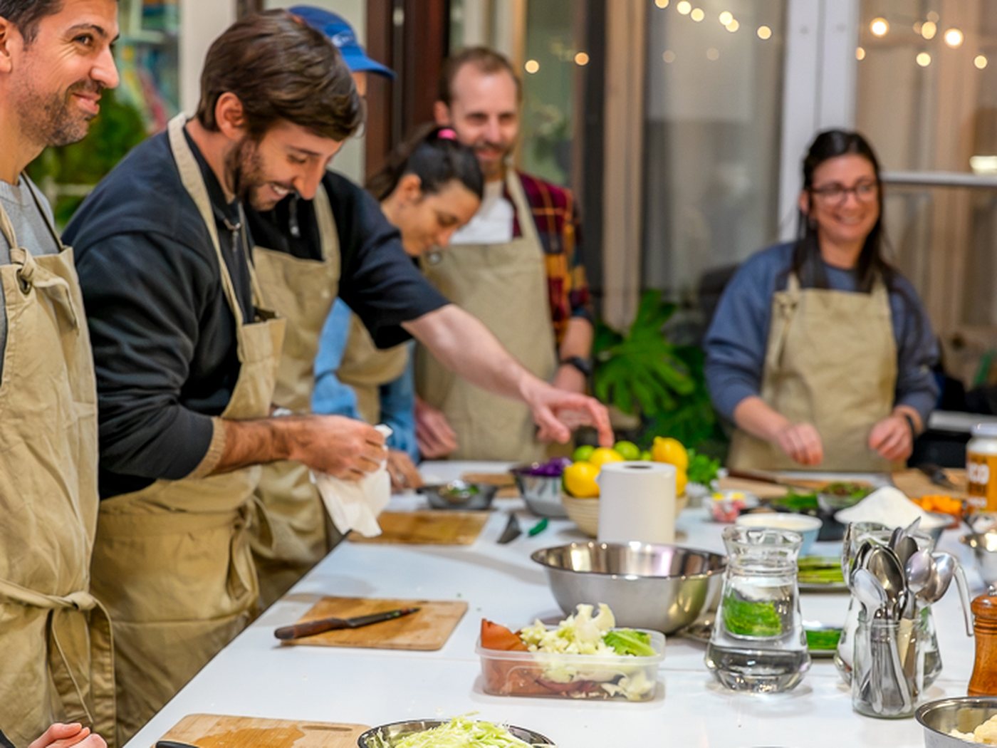 El grupo cocinando alrededor de la mesa larga de Clorofila, de noche